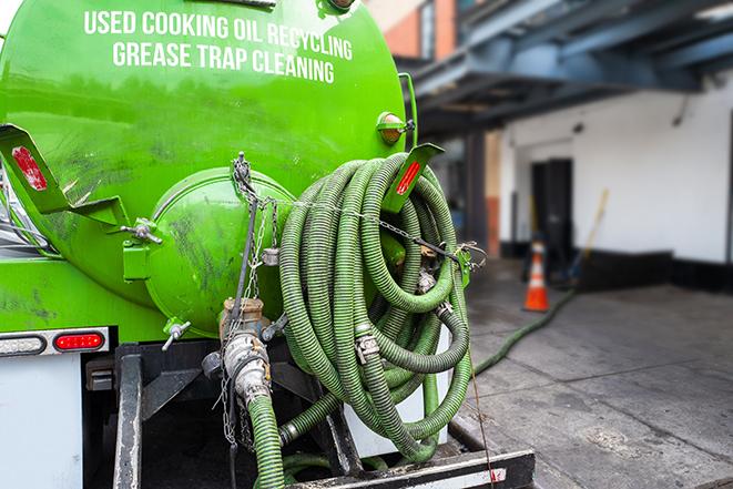 a technician pumping a grease trap in a commercial building in Jenison